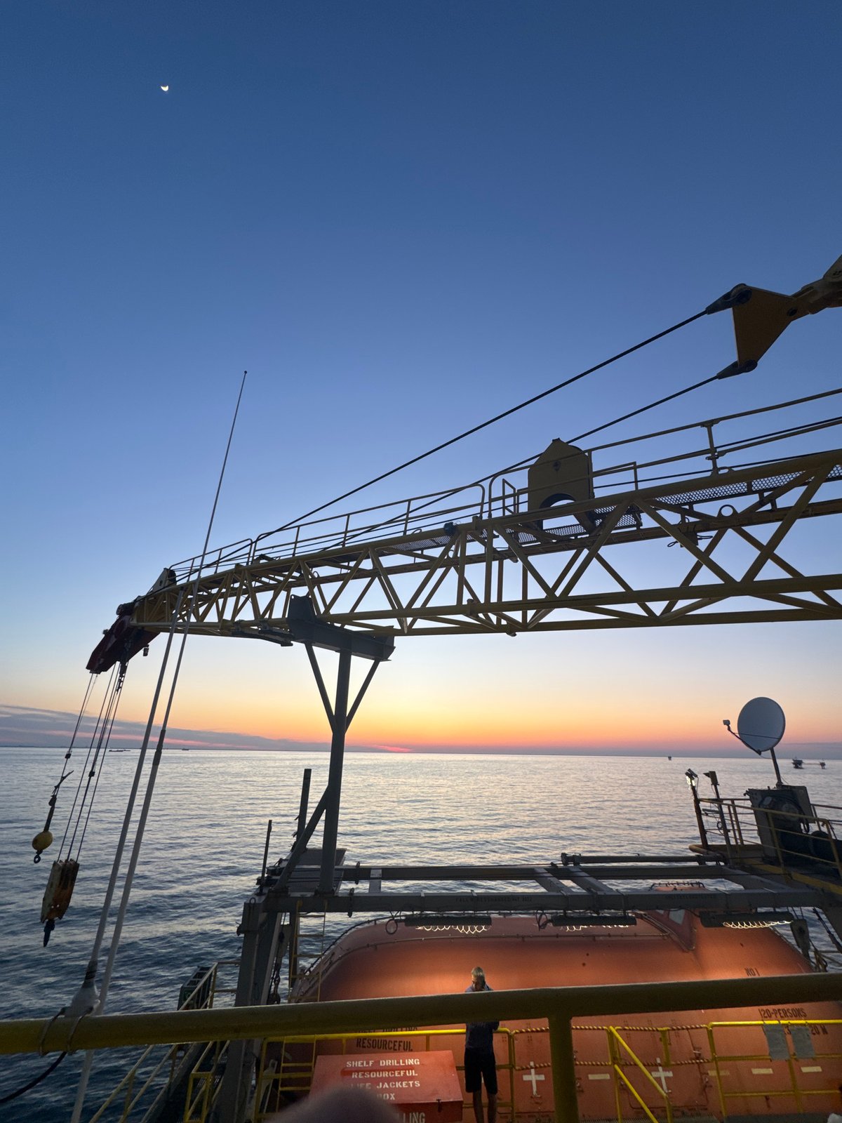Yellow offshore crane observed during sunset near Italian coast
