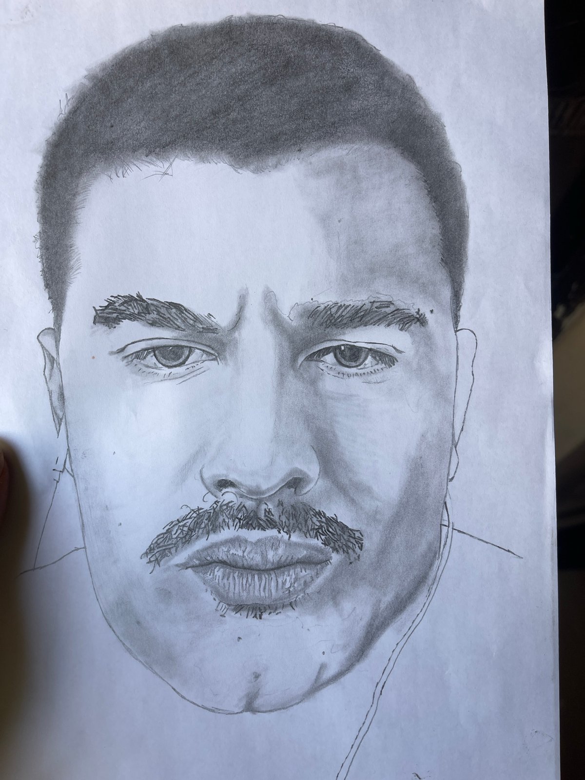 Artist creates pencil portrait from laptop reference in Jos
