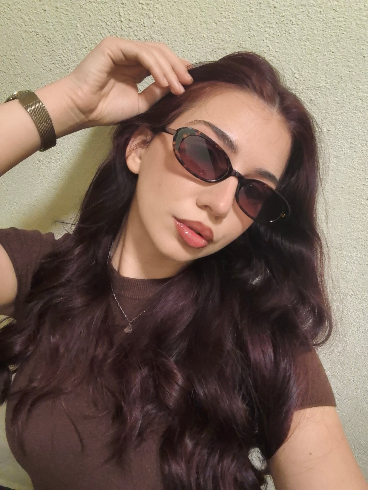 Woman takes indoor selfies wearing brown shirt and sunglasses