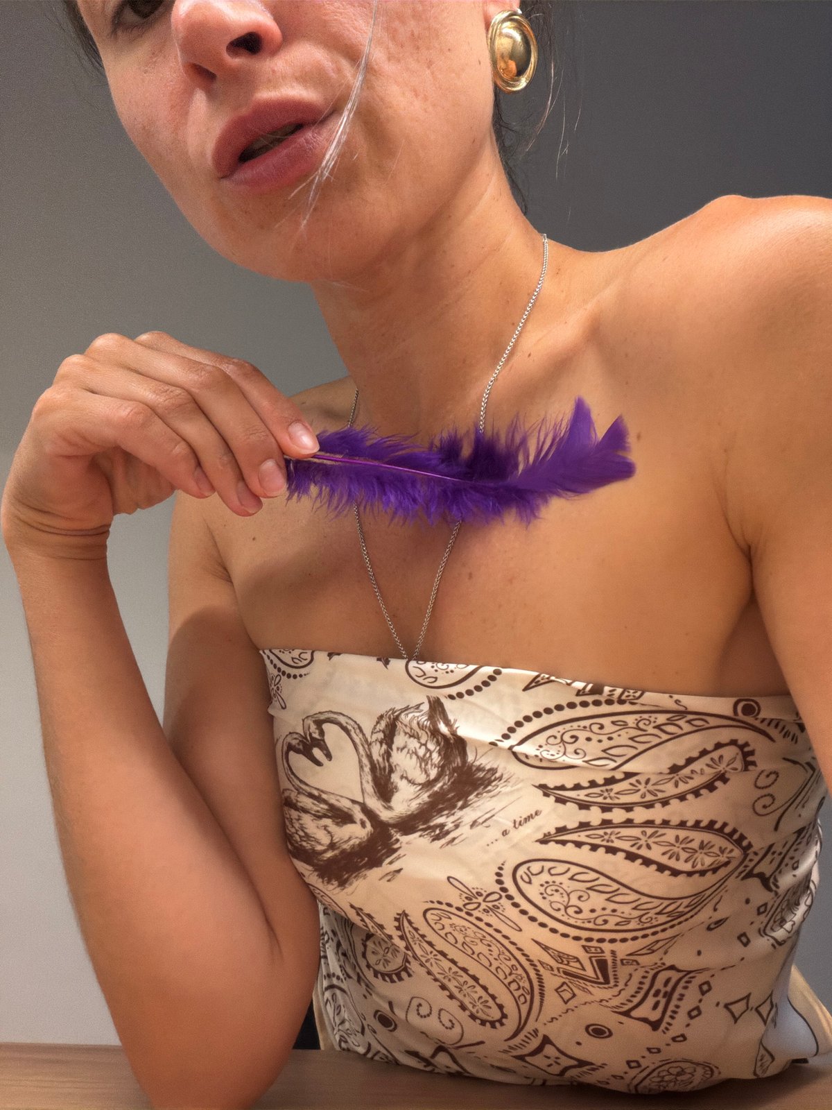 Woman poses with purple feather in intimate portrait session