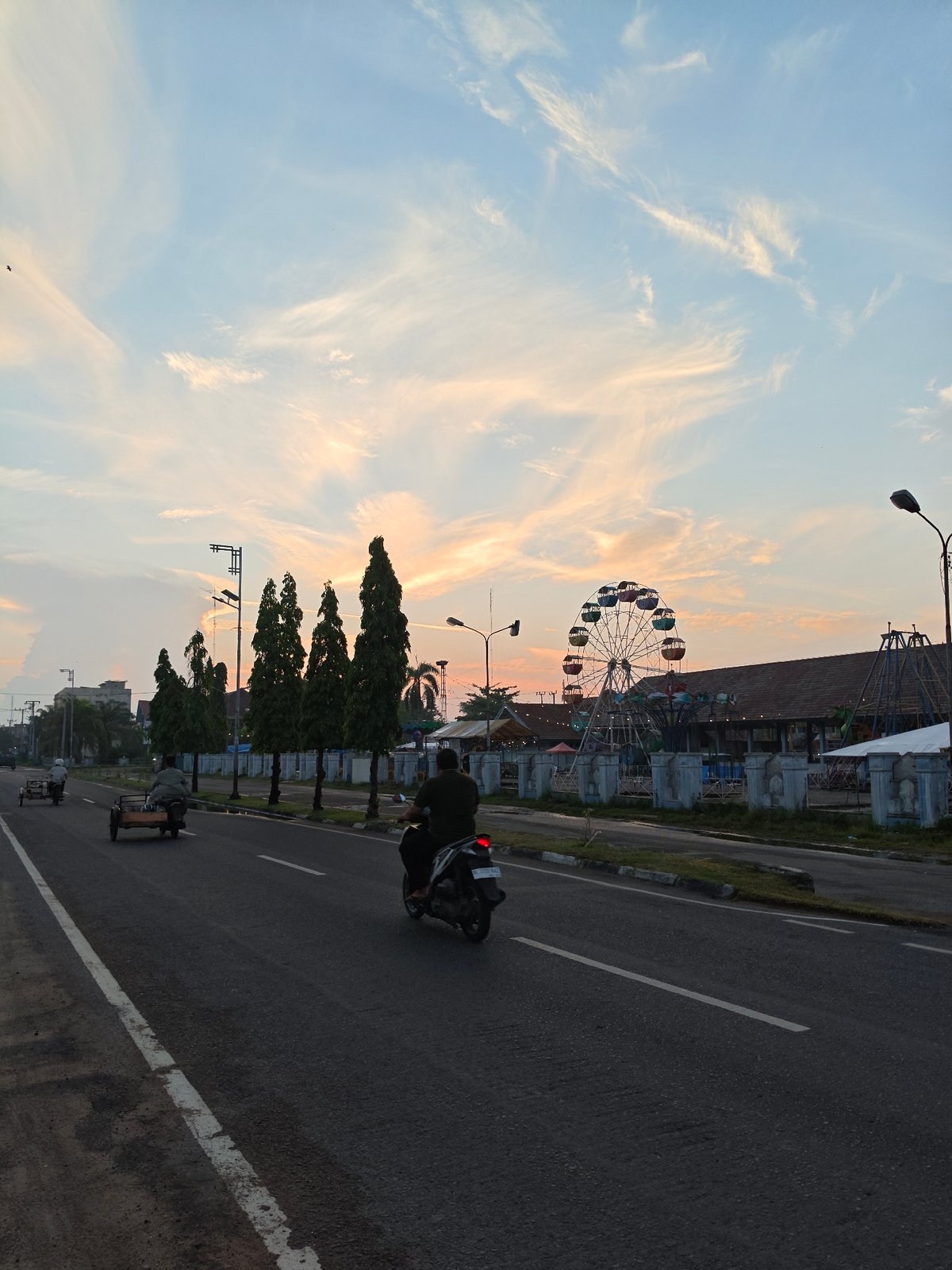Dusk scenes across Lhokseumawe streets and an amusement park