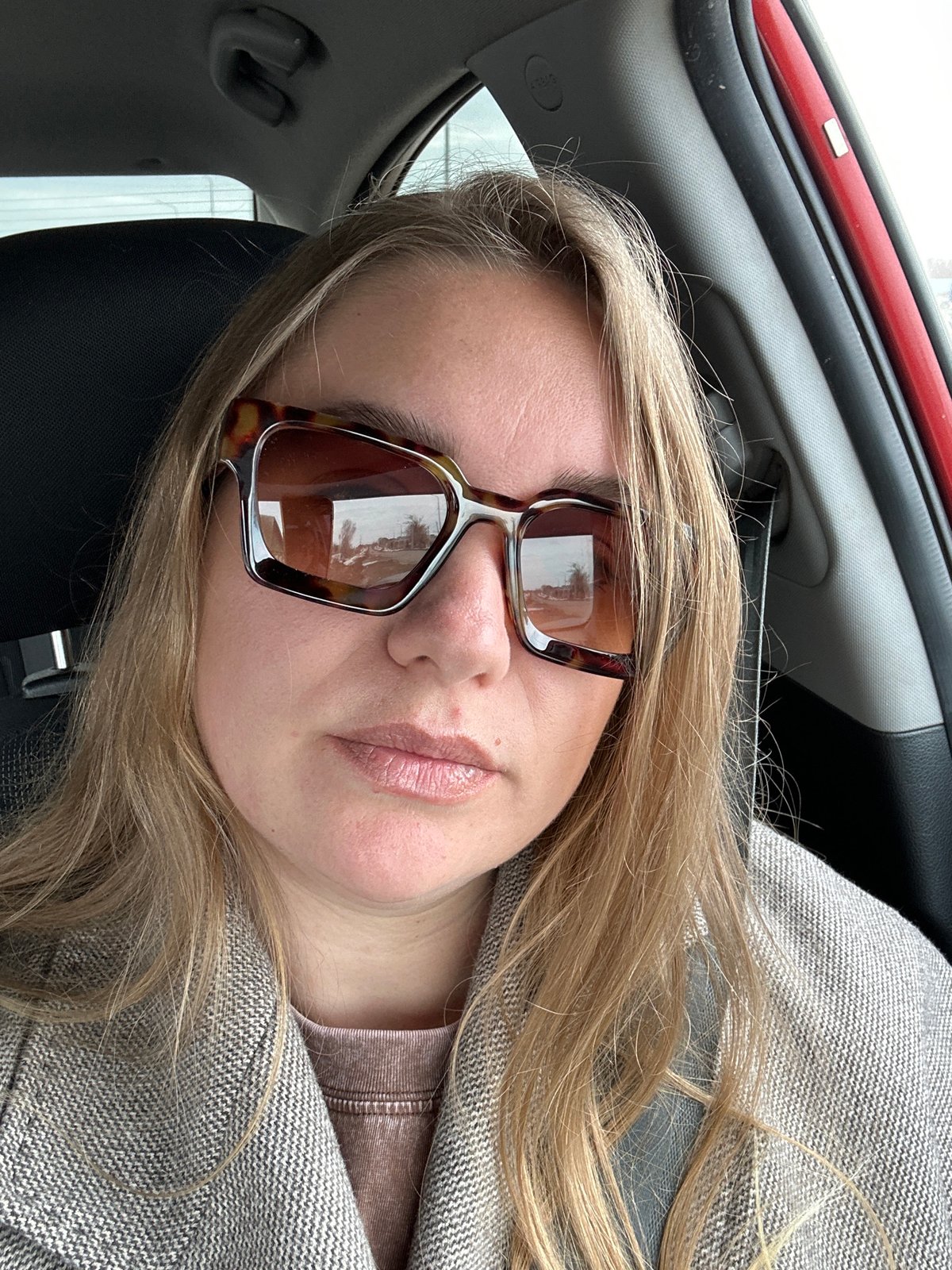 Woman in sunglasses sits in car in Russia