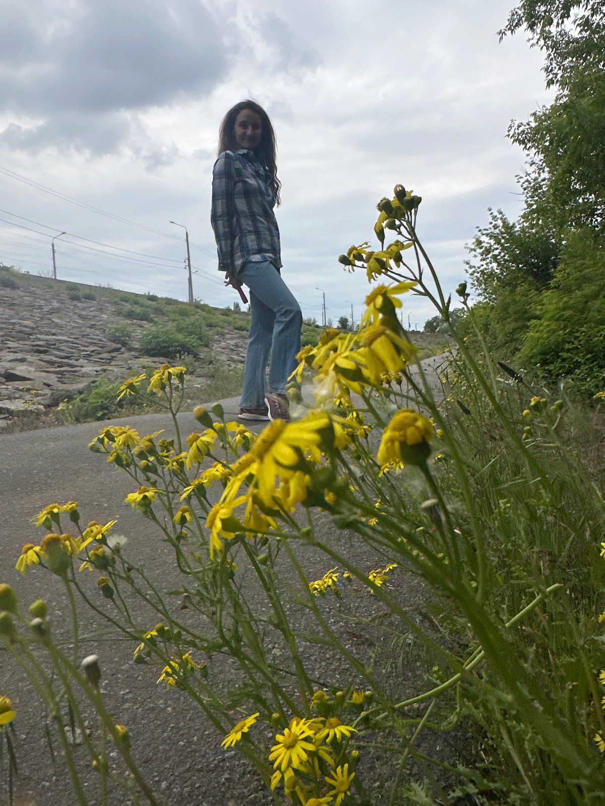 Woman dances on park path amid yellow flowers