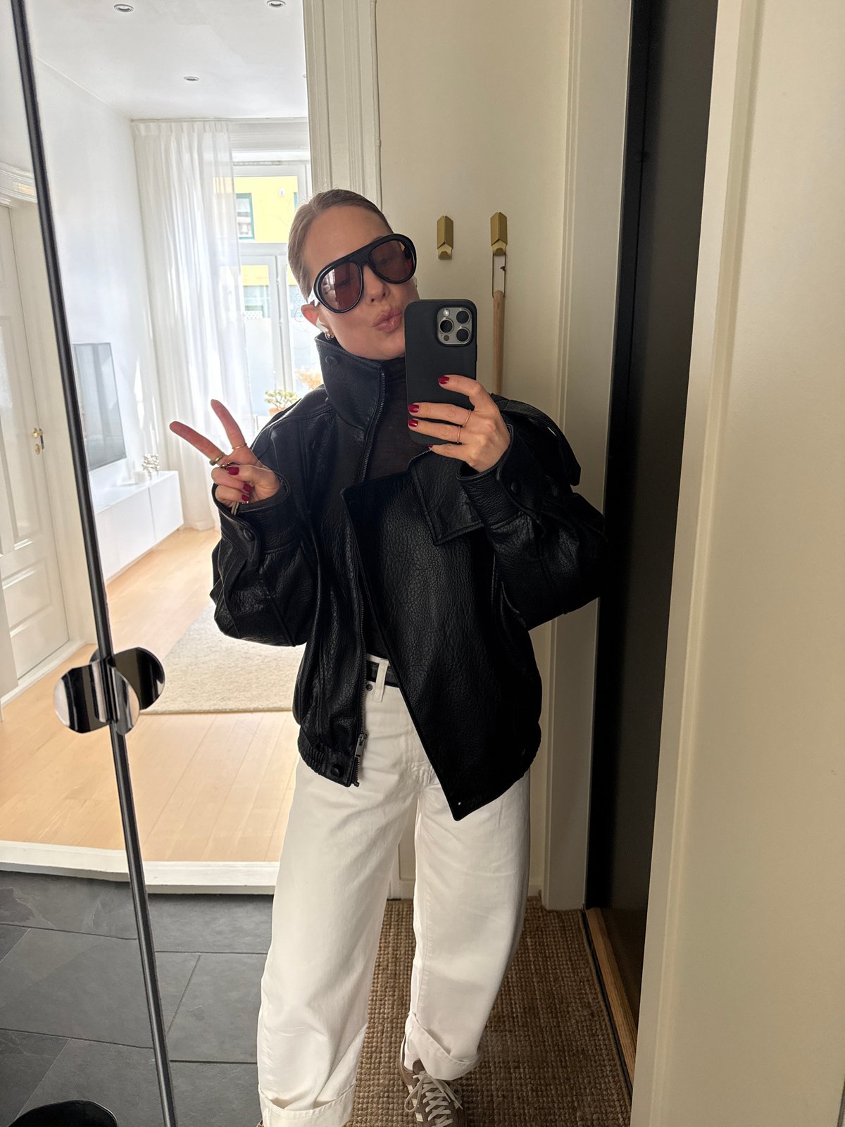 Person captures mirror selfie wearing leather jacket, sunglasses