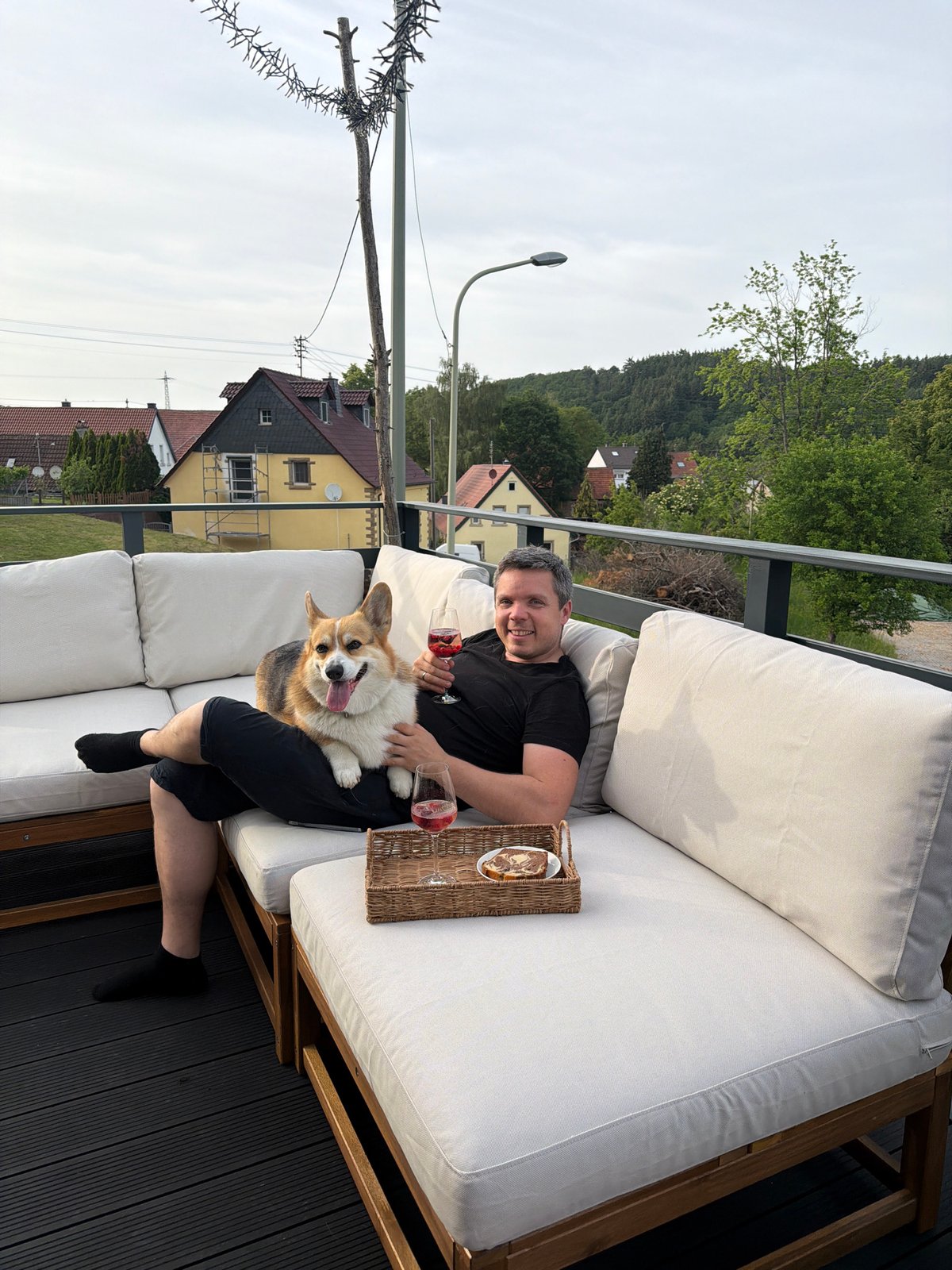 Man relaxes with corgi and wine on German terrace