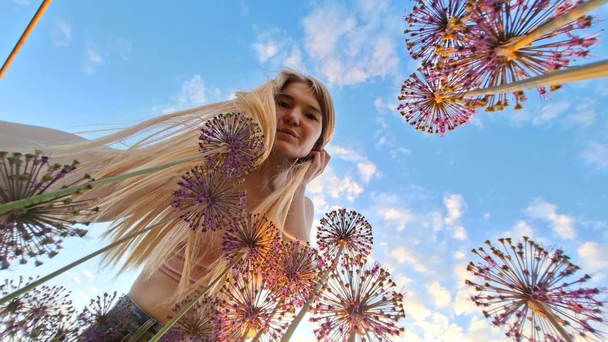 Woman photographs herself among purple flowers in Russian garden