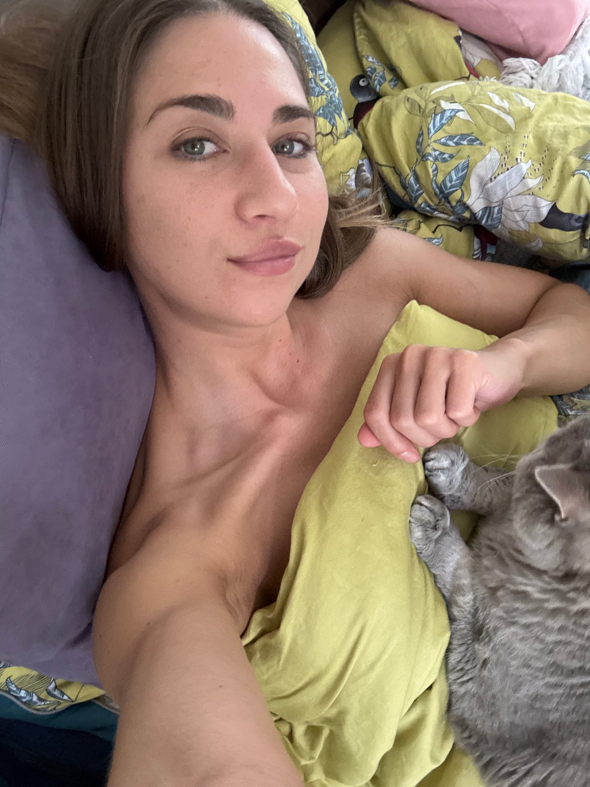 Woman takes morning selfies with gray cat in Russian bedroom