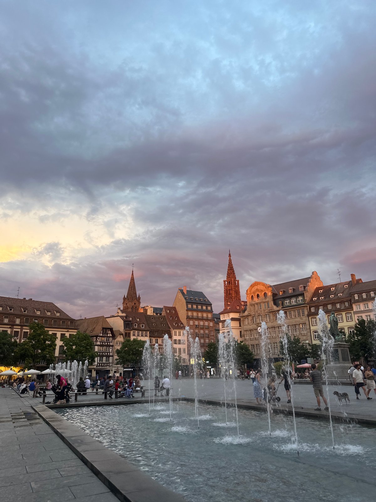 Strasbourg's cathedral square at dusk, fountain running