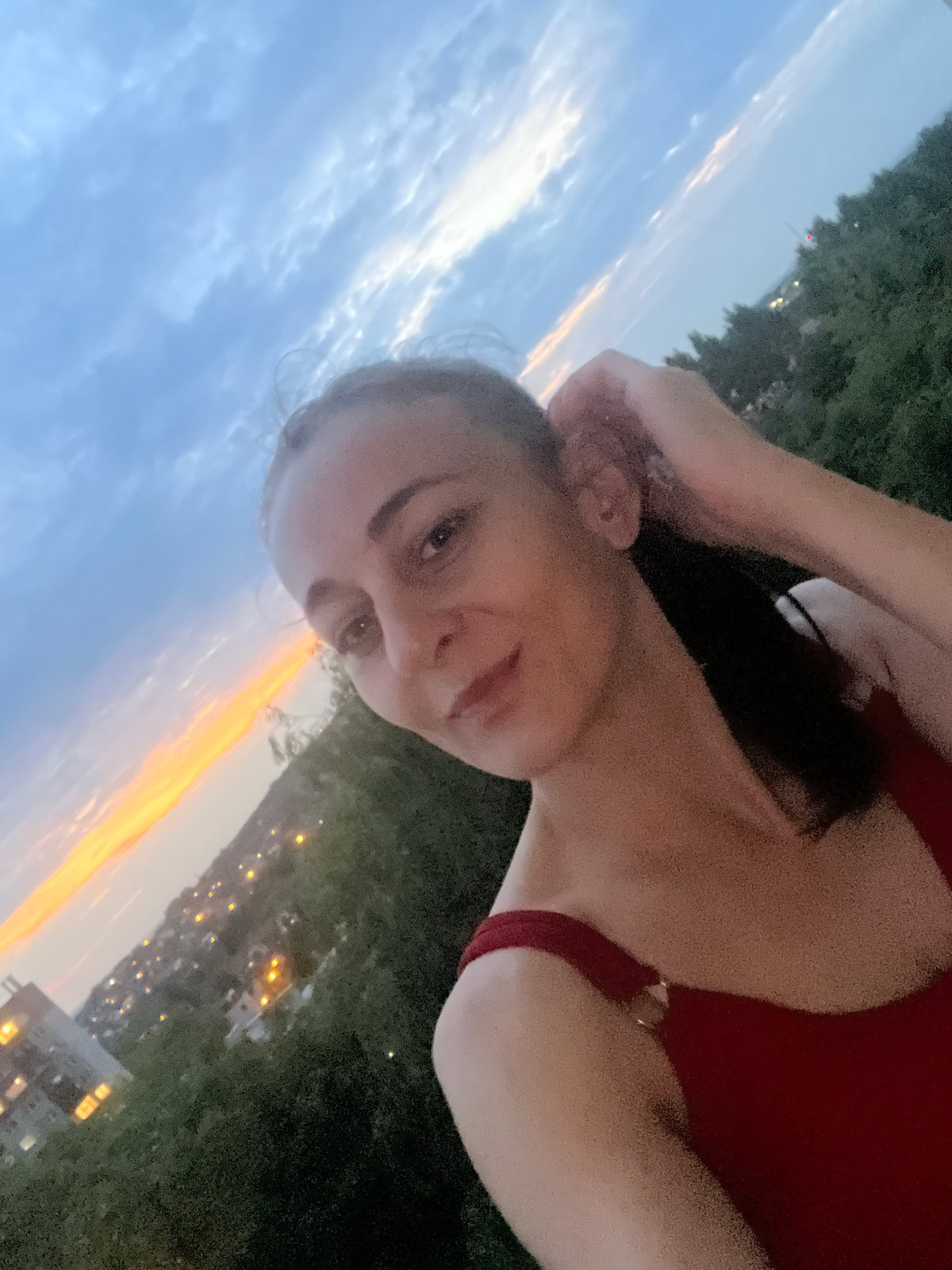 Rooftop-level sunset selfie session over a city skyline at dusk.