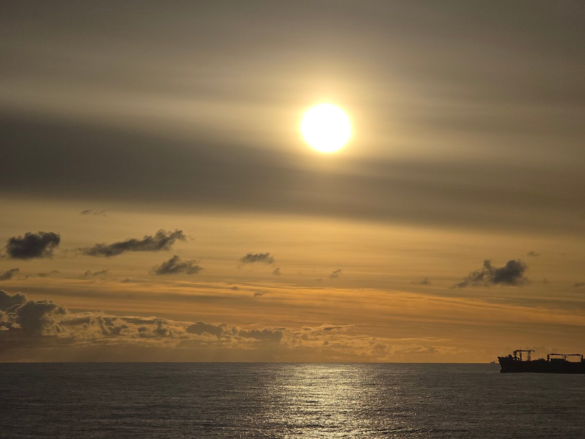 Ocean sunset observed with ship on horizon