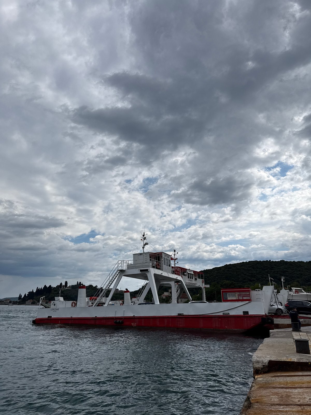Ferry docks at Montenegro pier amid mountainous coastline