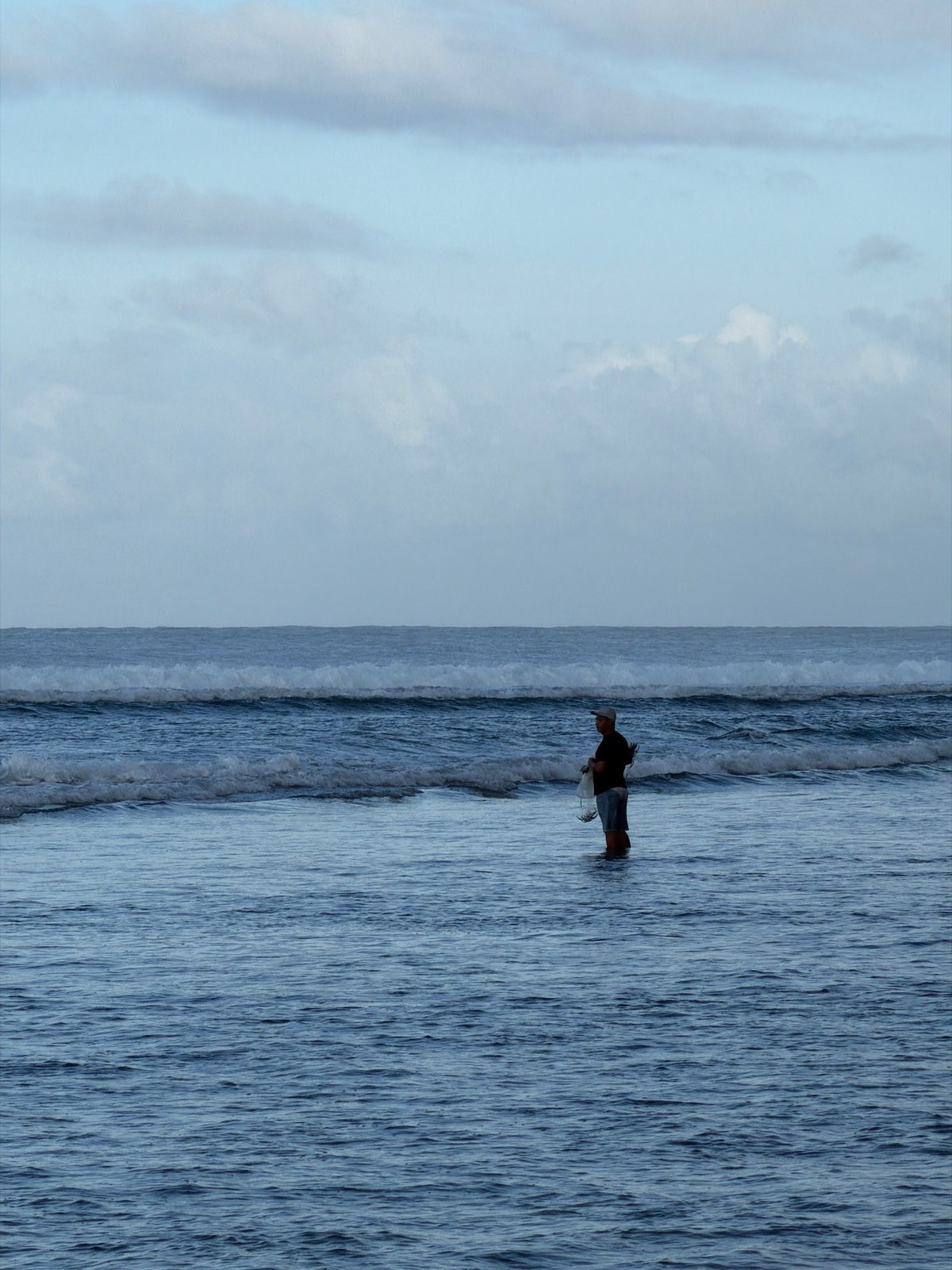 Person explores rocky coastline during low tide in Kuta Selatan
