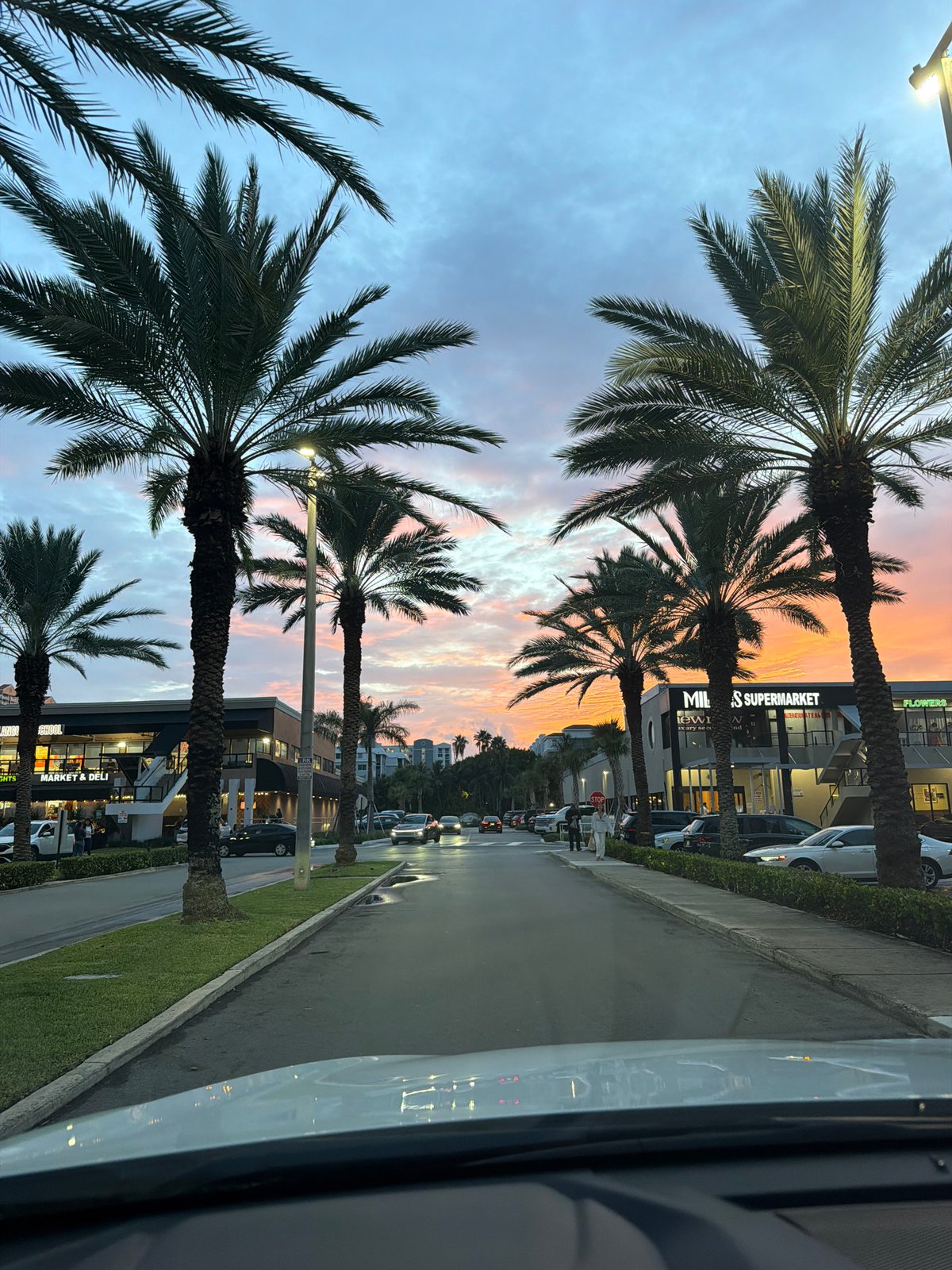 Palm-lined street glows under a vivid Sunny Isles dusk sky