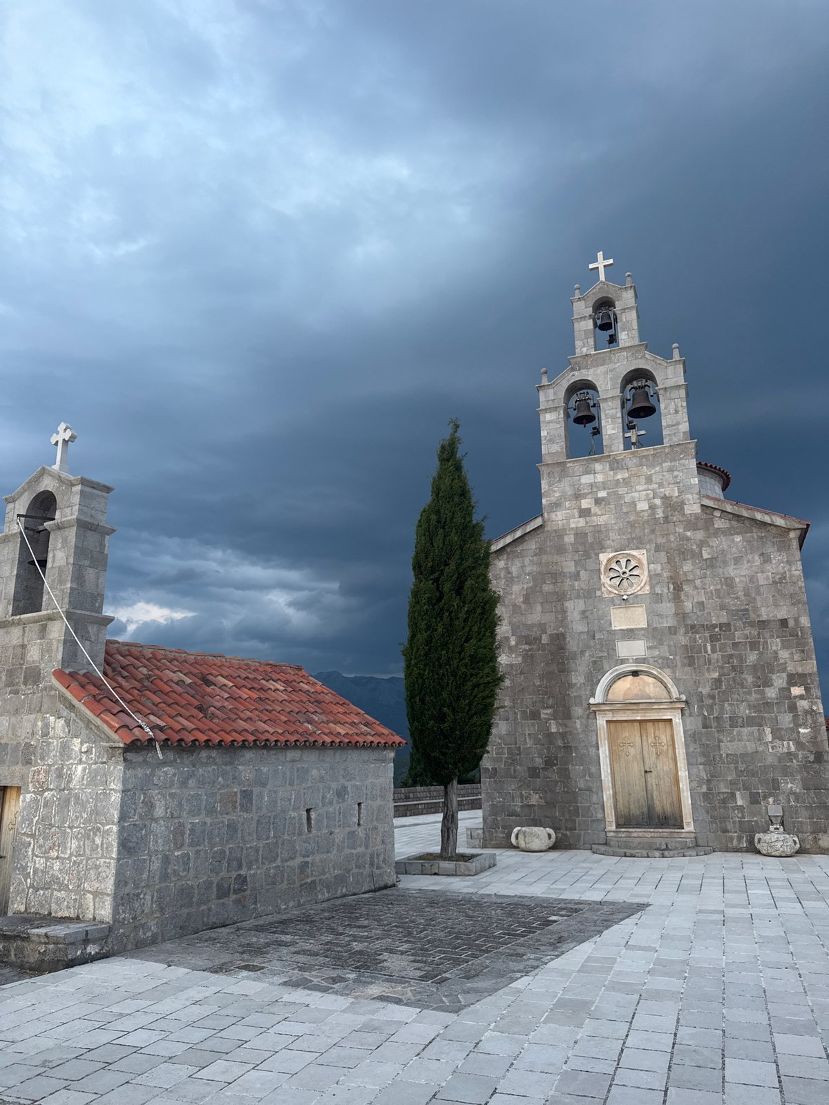 Stone churches and stormy skies over Kovačko Polje at dusk