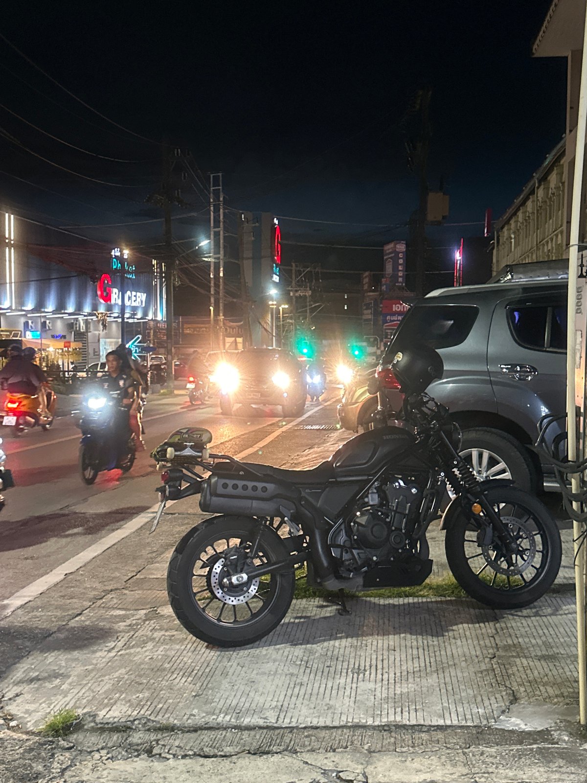 Motorcycle and skateboard parked on a Wichit sidewalk at night