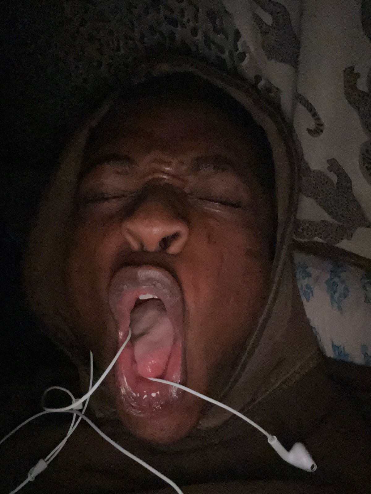 Person uses dental device in bed with earbuds