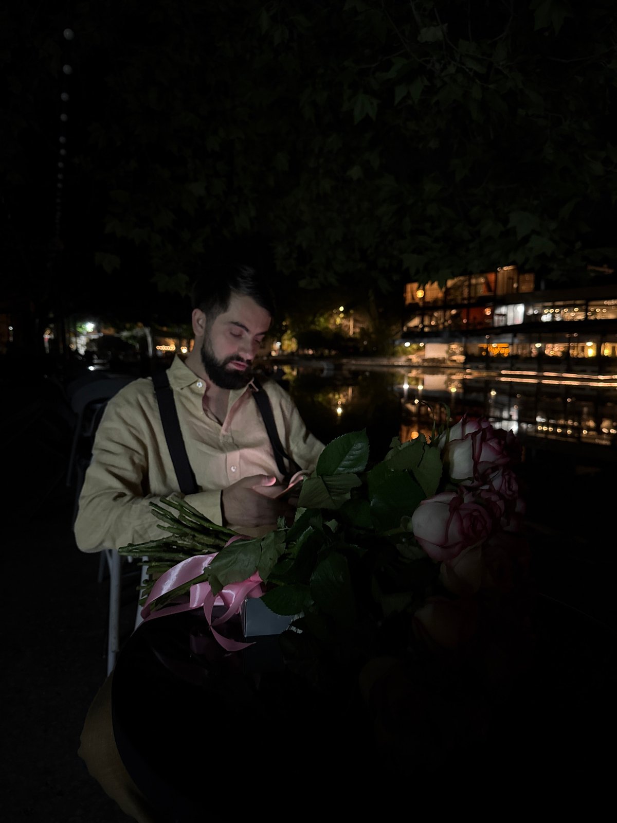 Man holds rose bouquet outdoors in Yerevan night scene