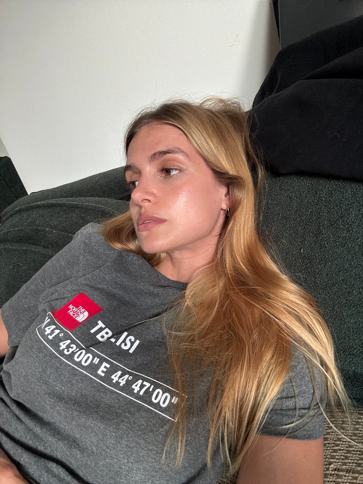 Woman in Tbilisi shirt rests on couch during soccer broadcast