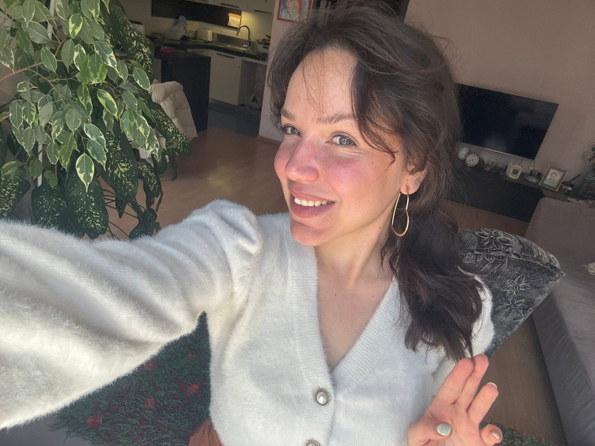 Woman takes selfies in white cardigan in Burgas apartment