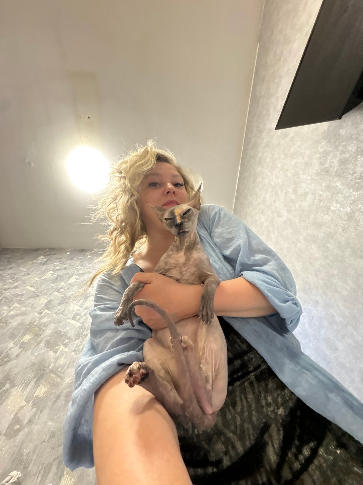 Woman cuddles hairless cat in Russian home