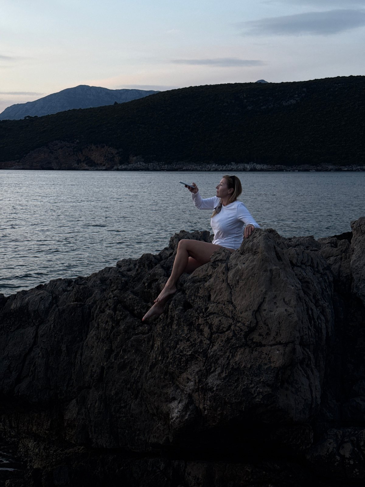 Woman with phone observed on Adriatic cliff in Montenegro