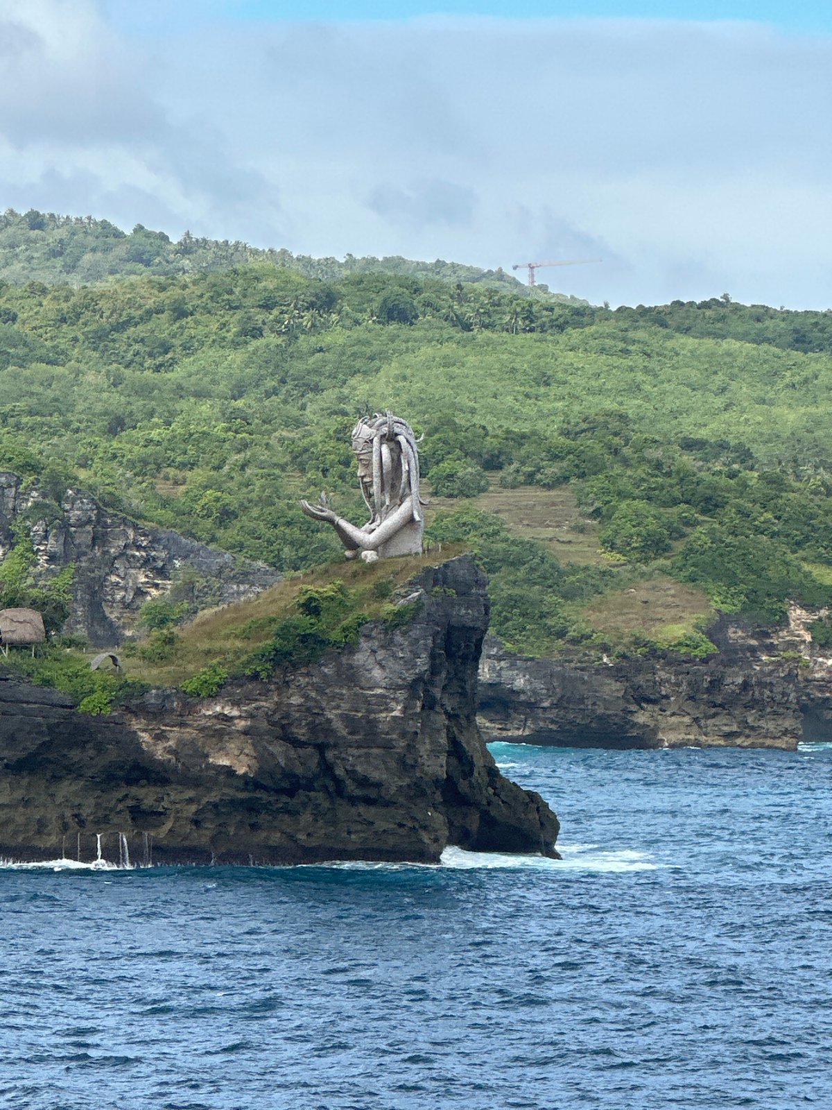 Stone woman statue observed on Nusa Penida cliff overlooking ocean