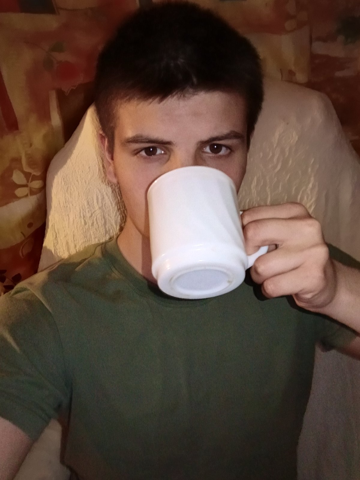 Young man drinks from mug in Russian home setting