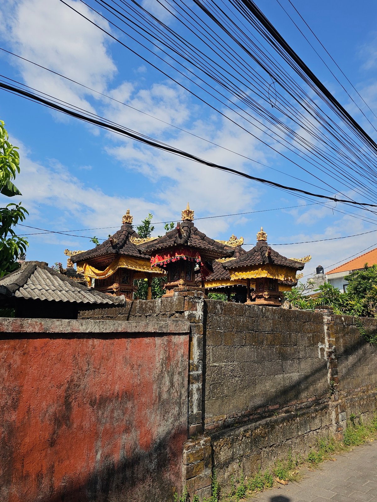Morning delivery operations near traditional Balinese temple in Denpasar
