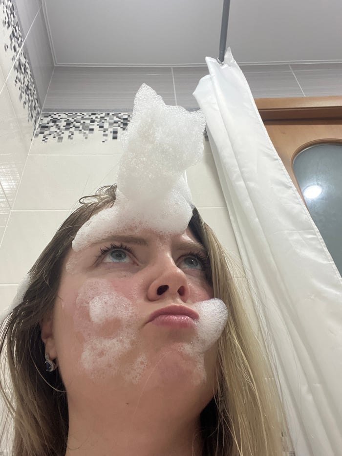 Woman performs skincare routine while cat watches in Chaikovsky
