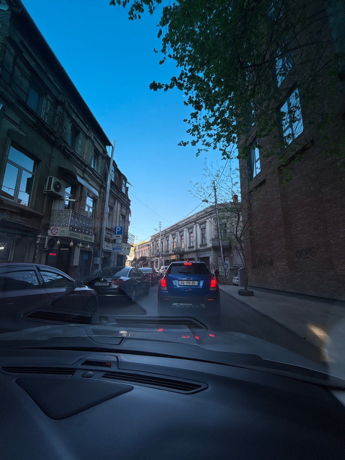 Driver documents mixed architecture during afternoon commute in Tbilisi