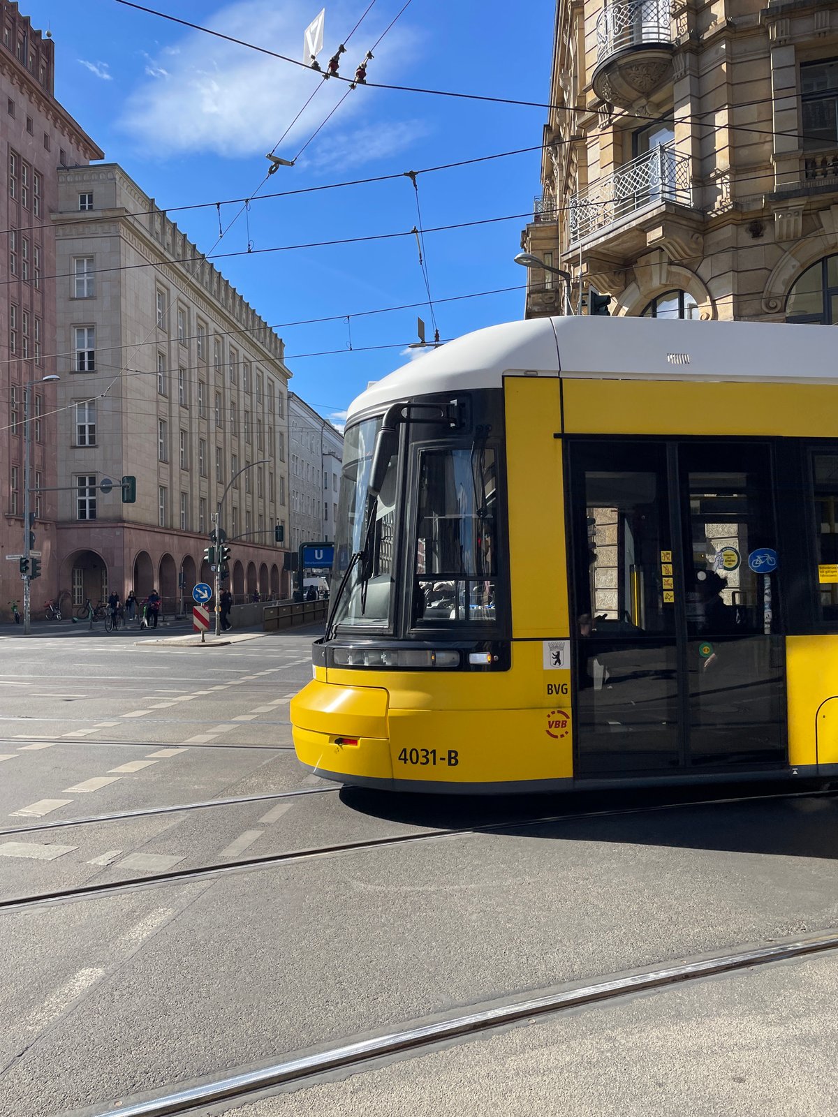 Berlin tram operates under sunny skies amid pedestrian traffic