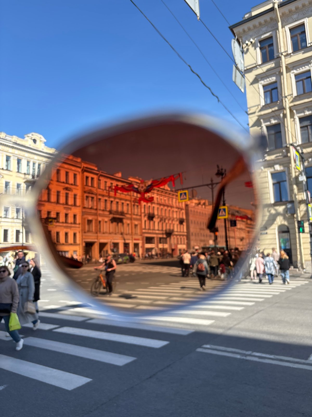 Sunglasses reflection captures Saint Petersburg street scene with red banners