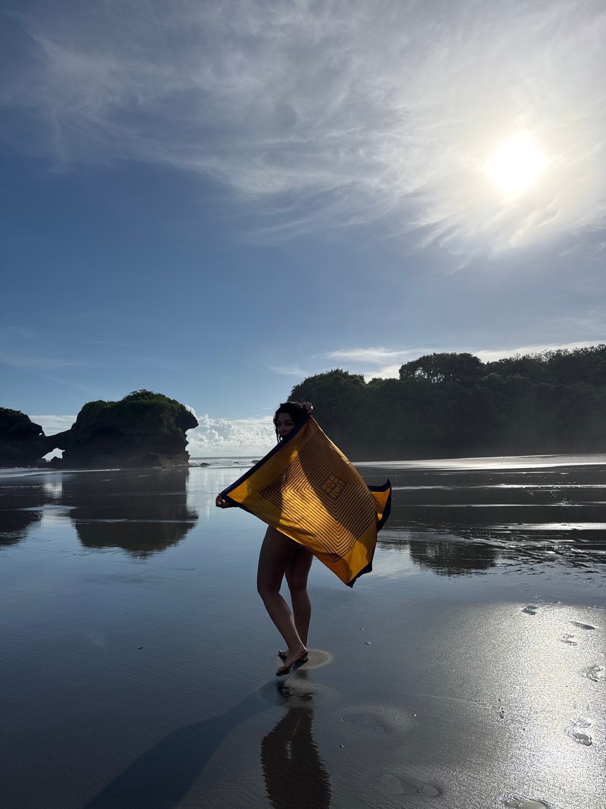 Person holds patterned cloth on Indonesian beach