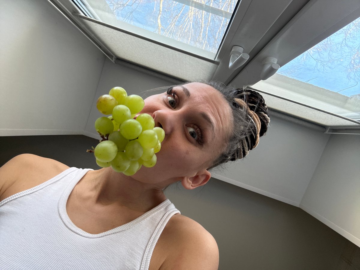 Woman with braided hair holds green grapes in morning sighting