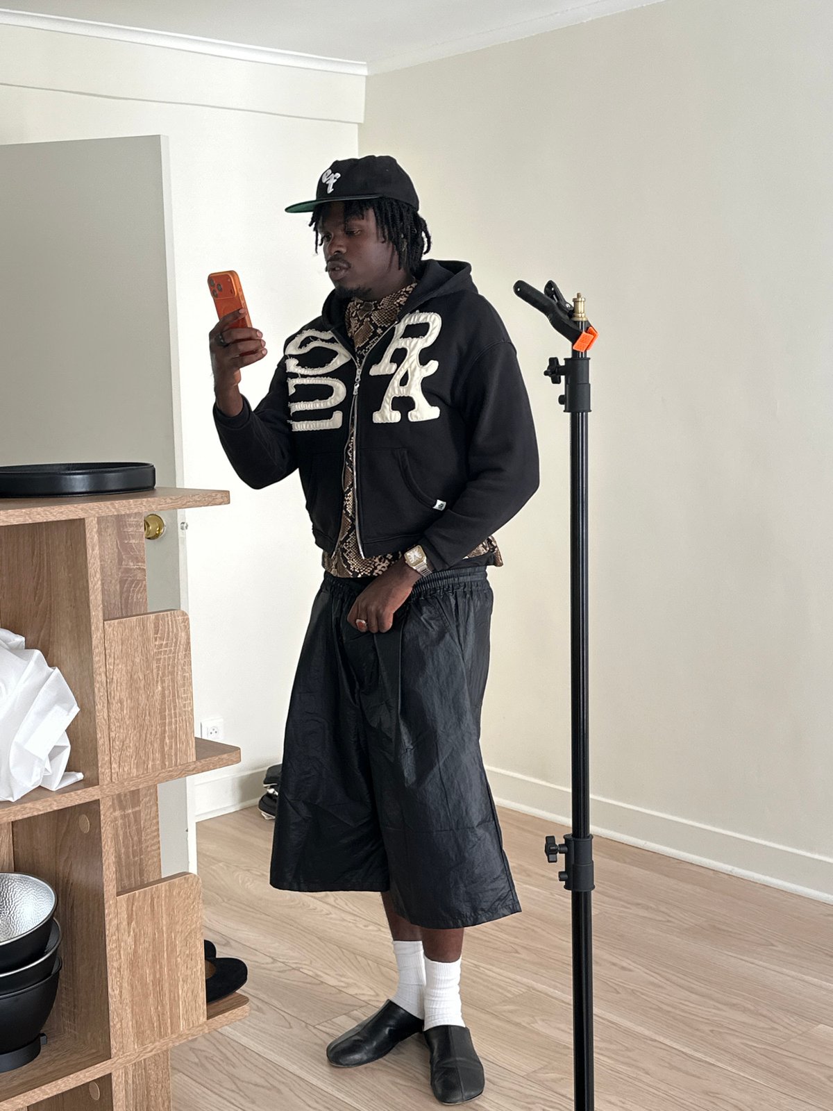 Man in black attire uses orange phone indoors in Paris