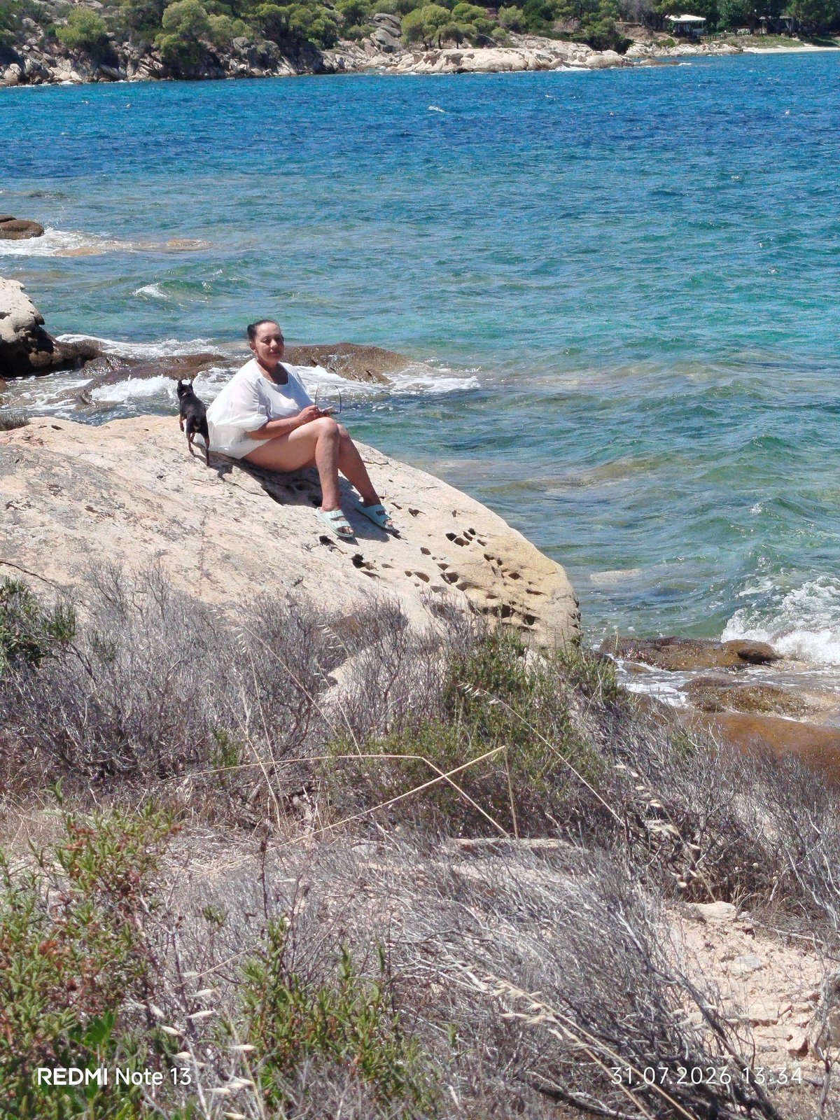 Sunny morning on the rocks in Sithonia with a small black dog