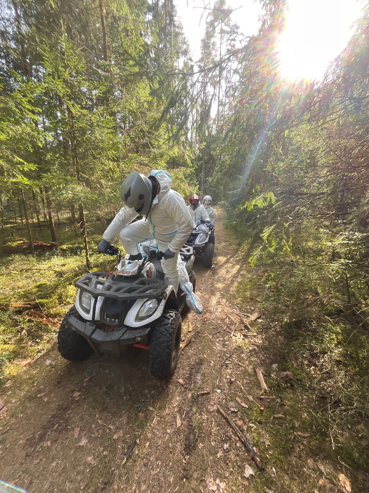 Protected riders operate ATVs with equipment in Russian forest