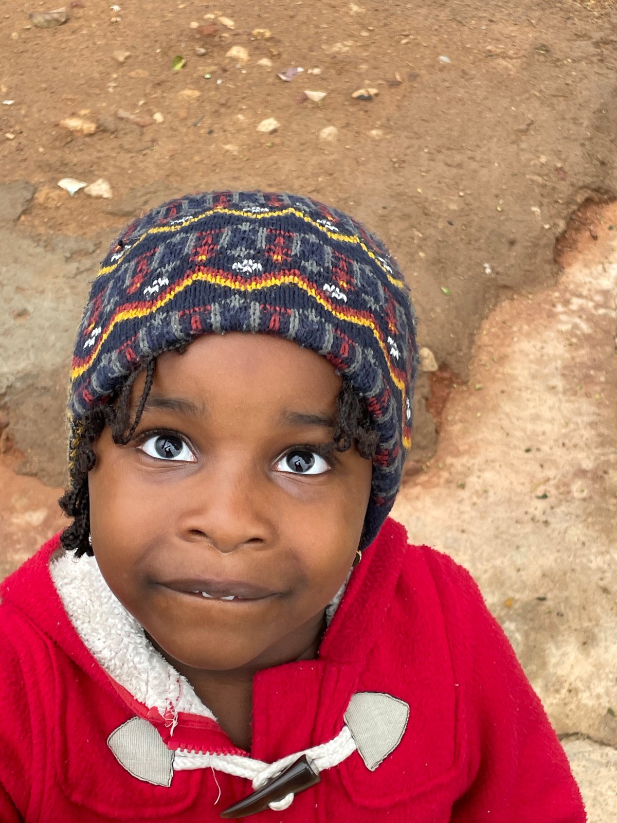 Child in red jacket photographed playing outdoors in Jos