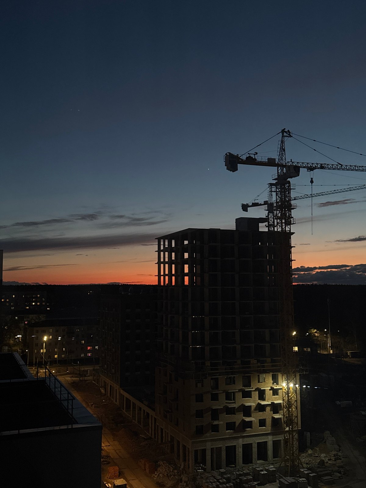 Tower cranes silhouetted at Izhevsk construction site during sunset