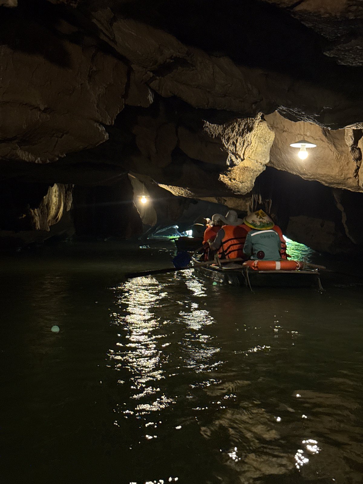 Tourists boat beneath ornate wooden structure in Hoa Lư Ward