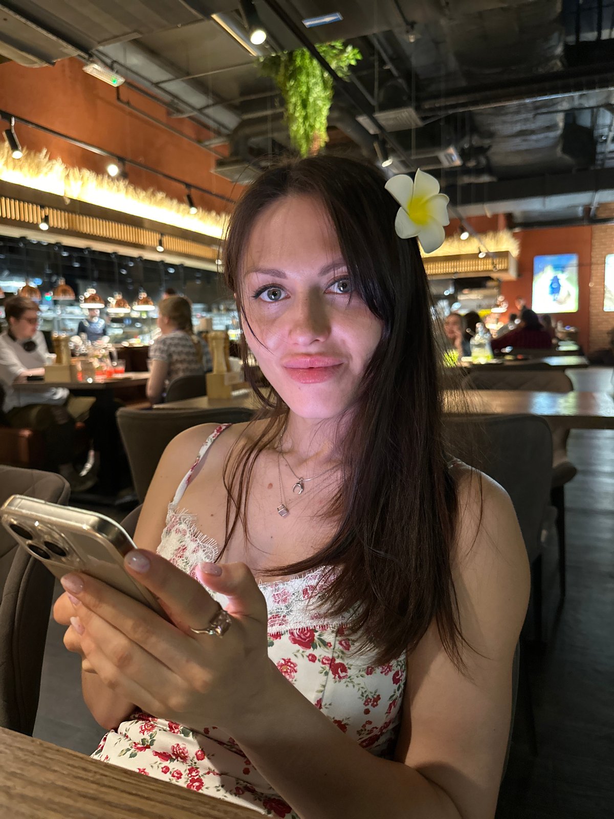 Woman with flower uses phone at Saint Petersburg restaurant