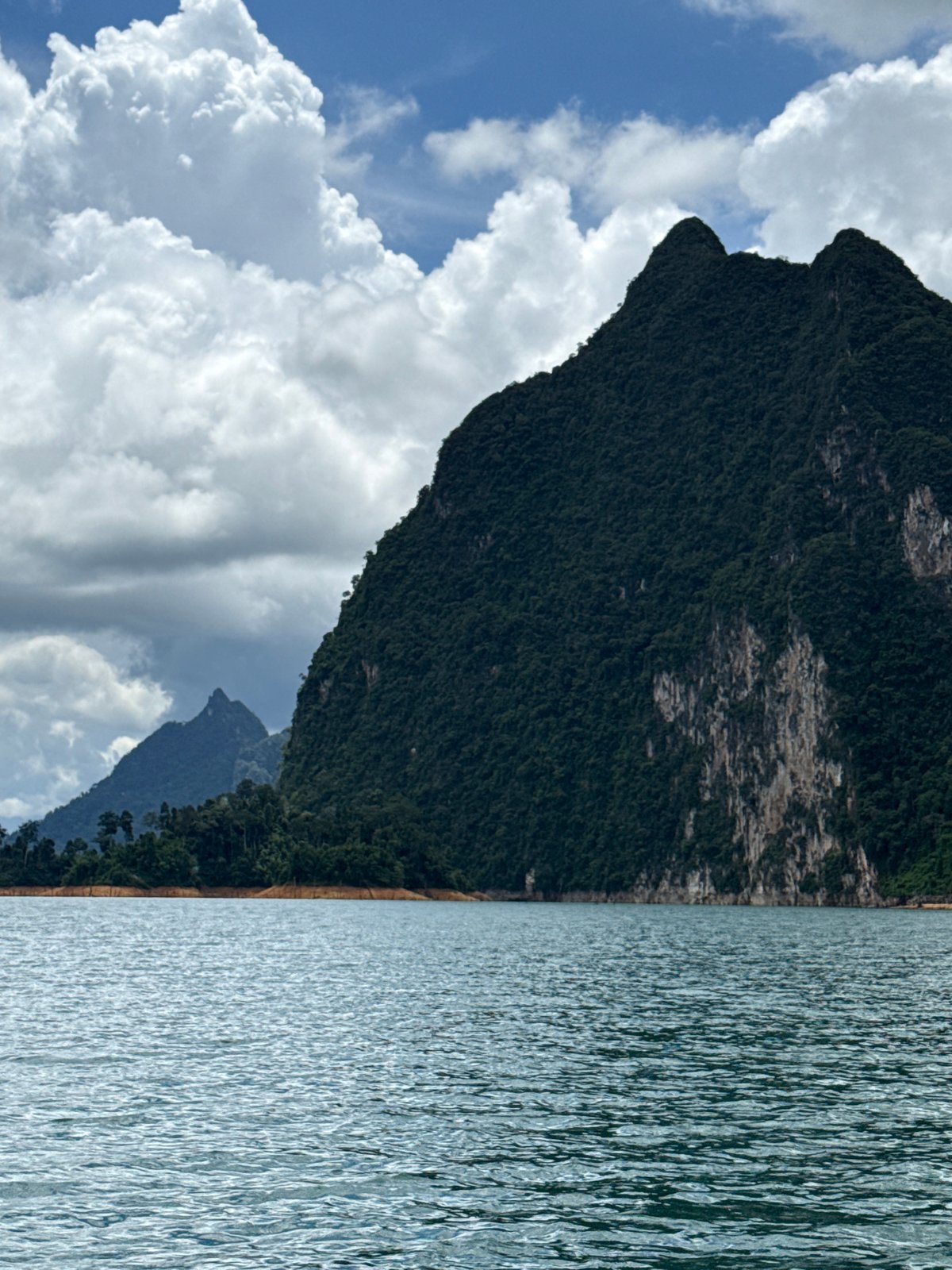 Limestone karsts rise from calm water at Khao Phang