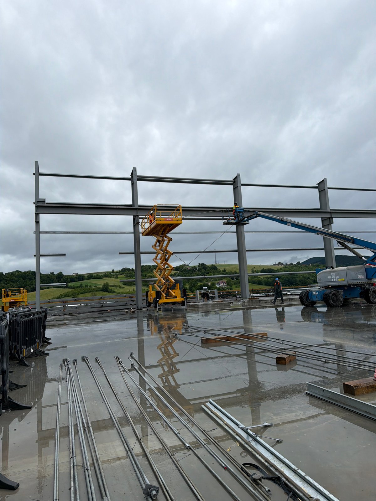 Construction crew works industrial site in cloudy Janowice morning