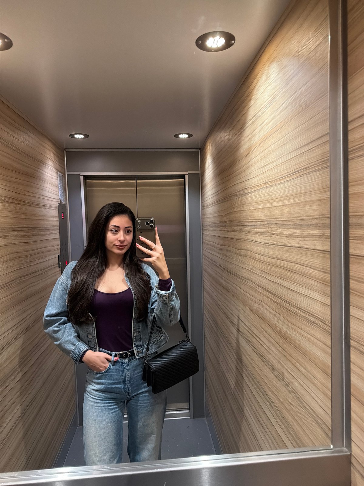 Woman takes selfie in wooden-paneled elevator in Sofia