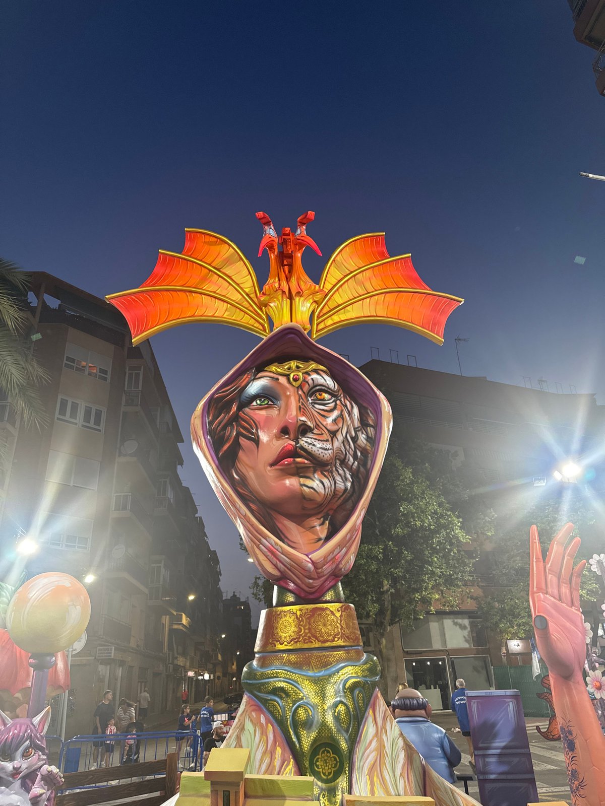 Giant effigy towers over a street scene at dusk