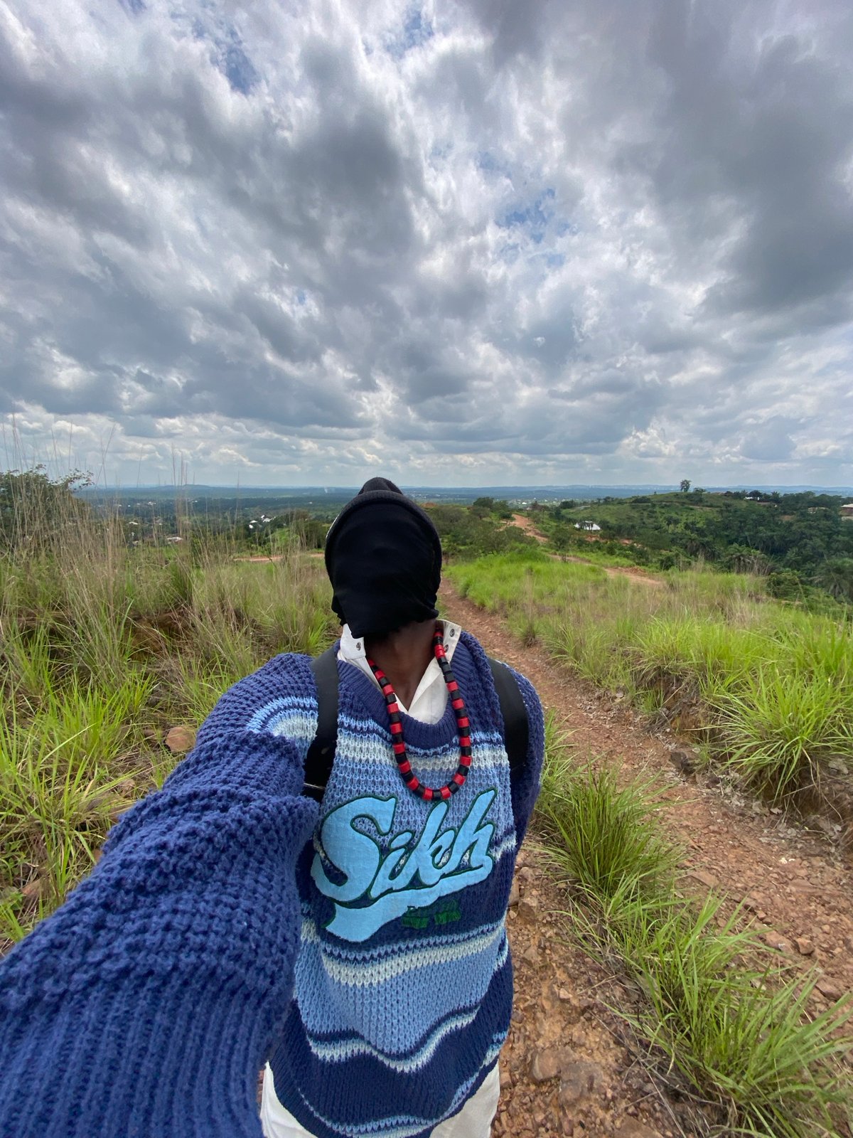 Pausing on a dirt path in Nigeria's hilly countryside