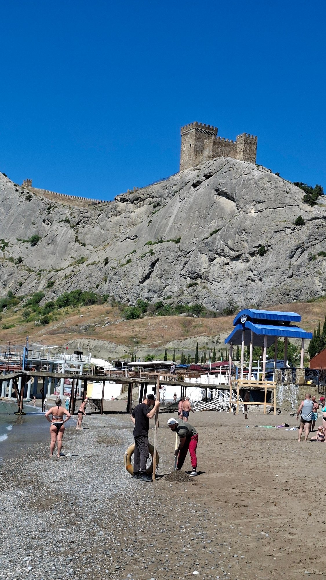 Children play at sunny coastal playground near historic castle