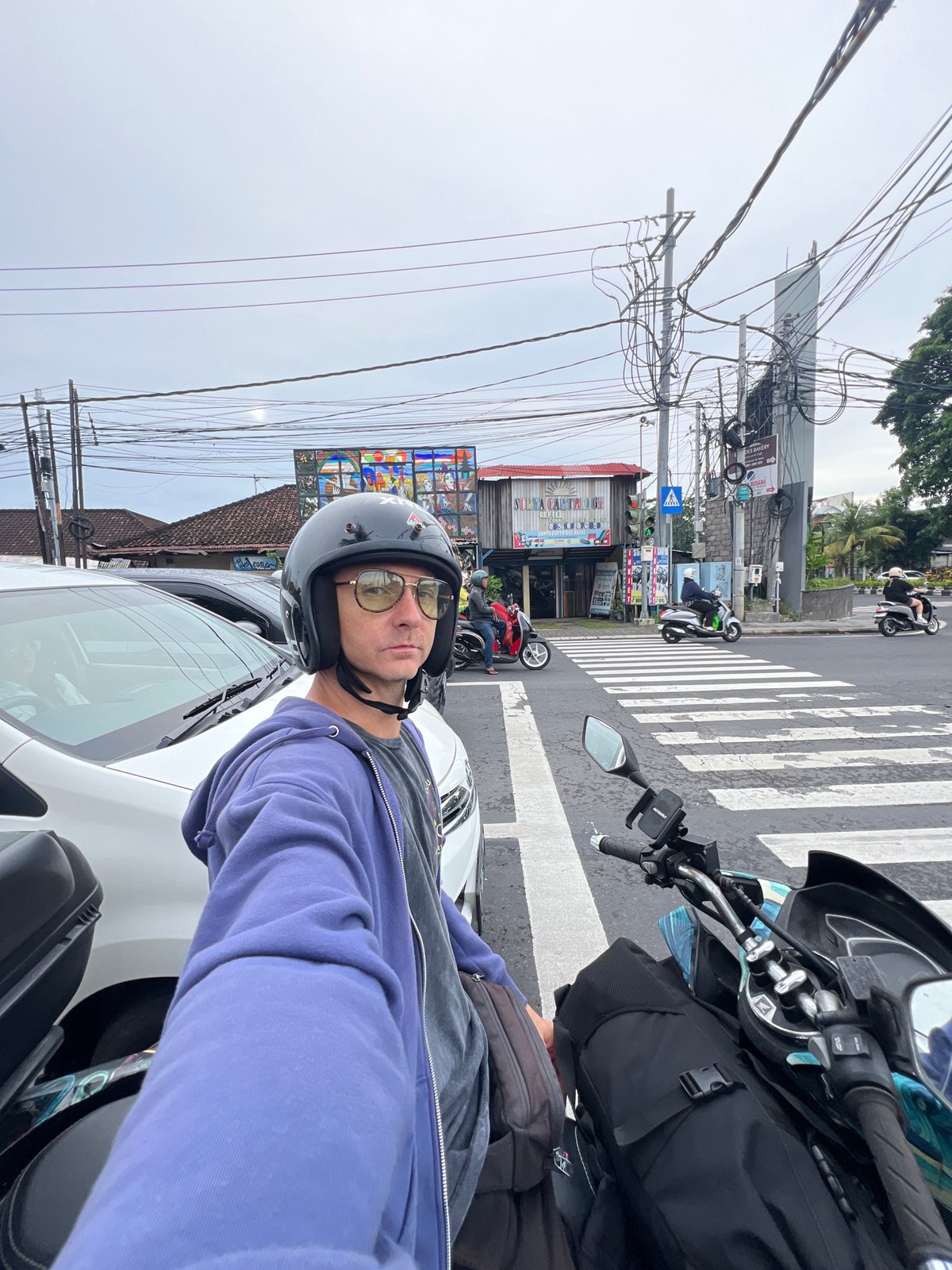 Motorcyclist takes selfie at wet Denpasar crosswalk after rain