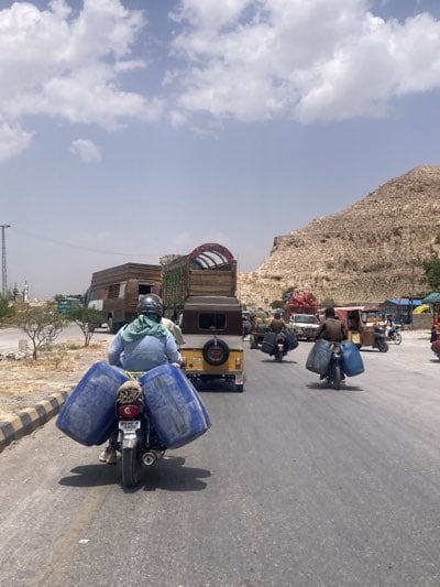 Motorcycle carries large containers through heavy Quetta traffic