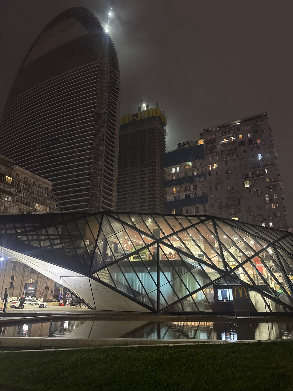 Nighttime urban scene centers on modern glass McDonald's restaurant